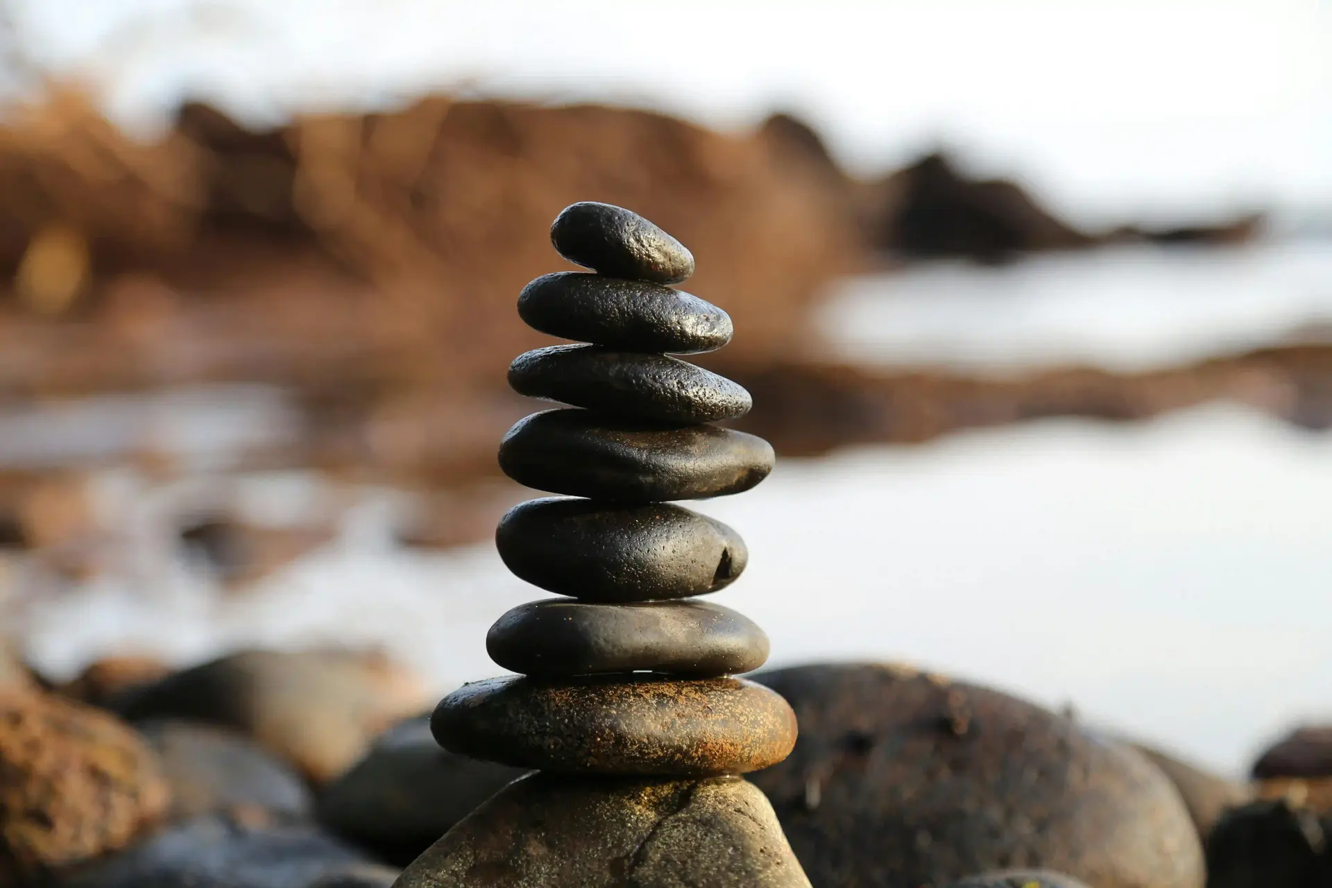 Stacked rocks balancing on the beach to indicate the balance that working with a psychiatrist or therapist can bring