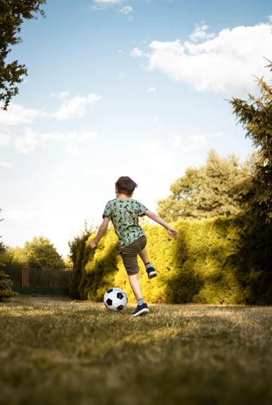 A young boy in a meadow playing with a soccer ball as a recreational activity for functional therapy in Wake Forest